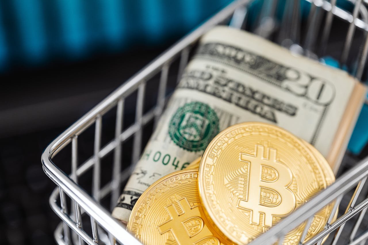 Close-up of bitcoin coins and US dollar bills in a small shopping cart, symbolizing online shopping and cryptocurrency investment.